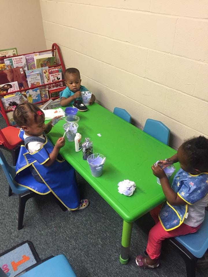Three children at a green table with craft supplies