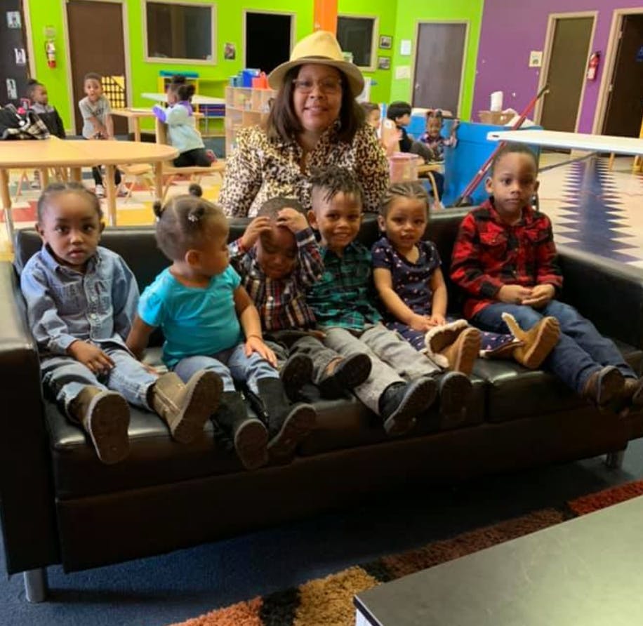 Adult and multiple children sitting on a couch in a classroom