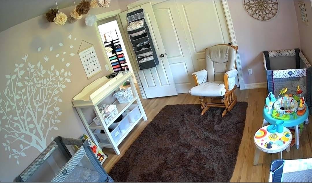 Baby nursery room with a changing table rocking chair and playpens