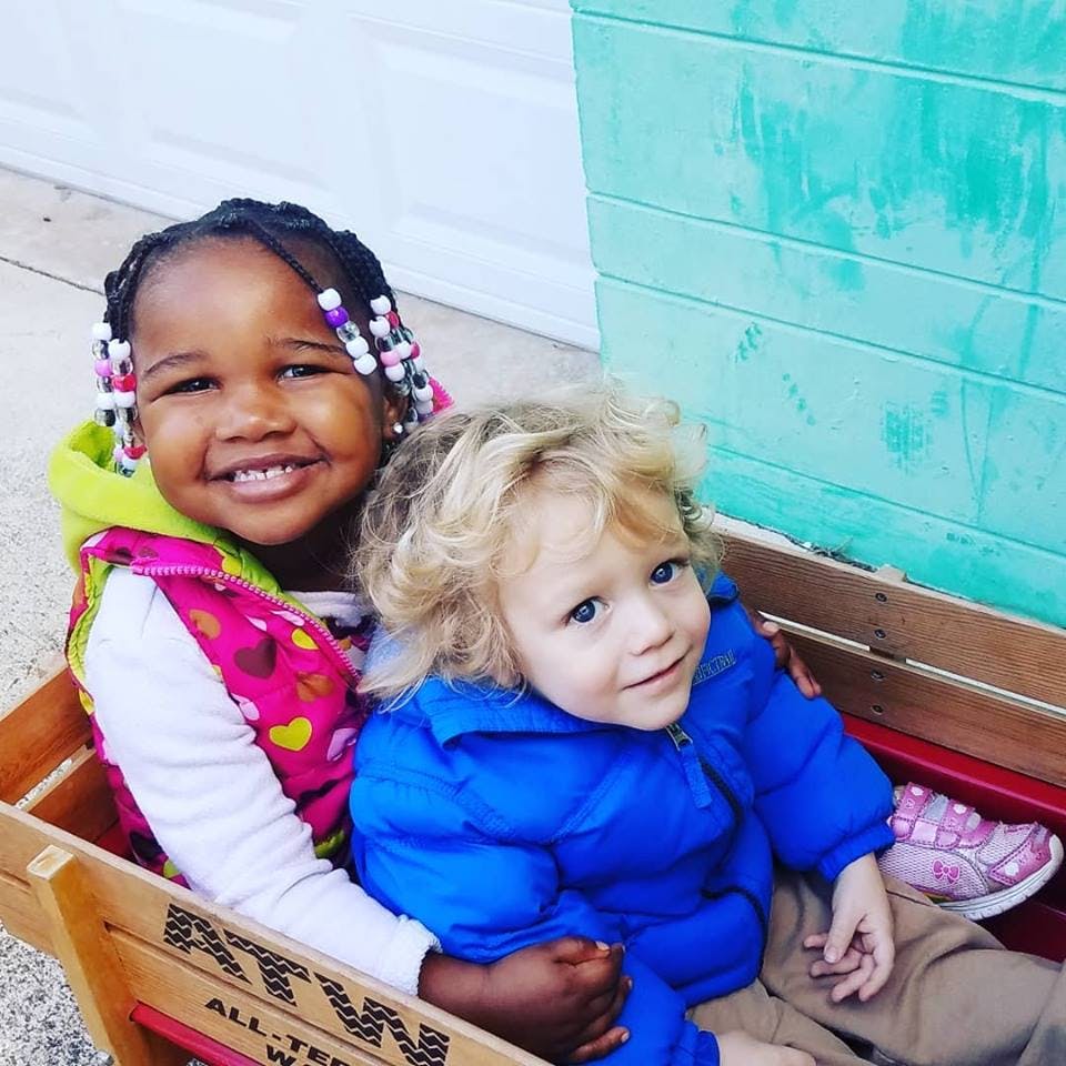 Two children sitting in a wooden wagon