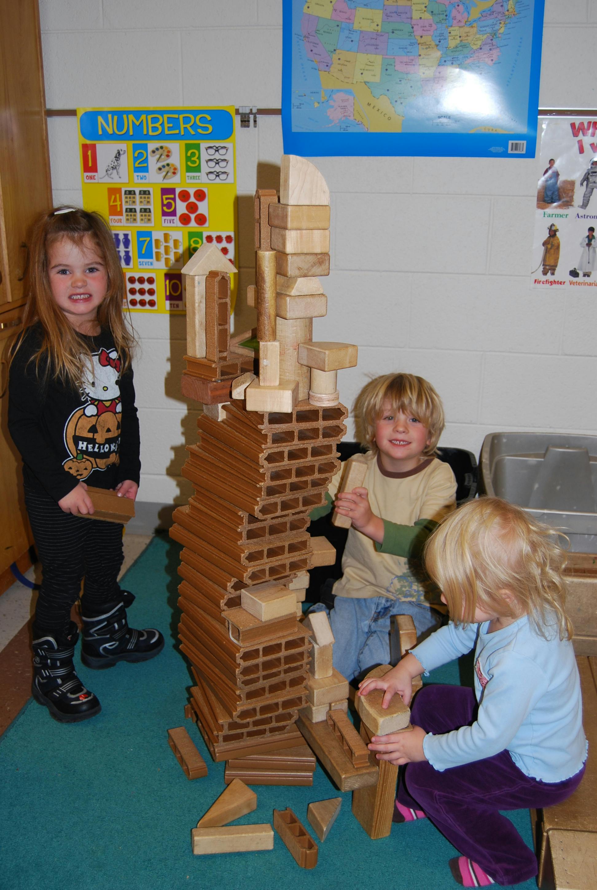 Three children playing with wooden building blocks