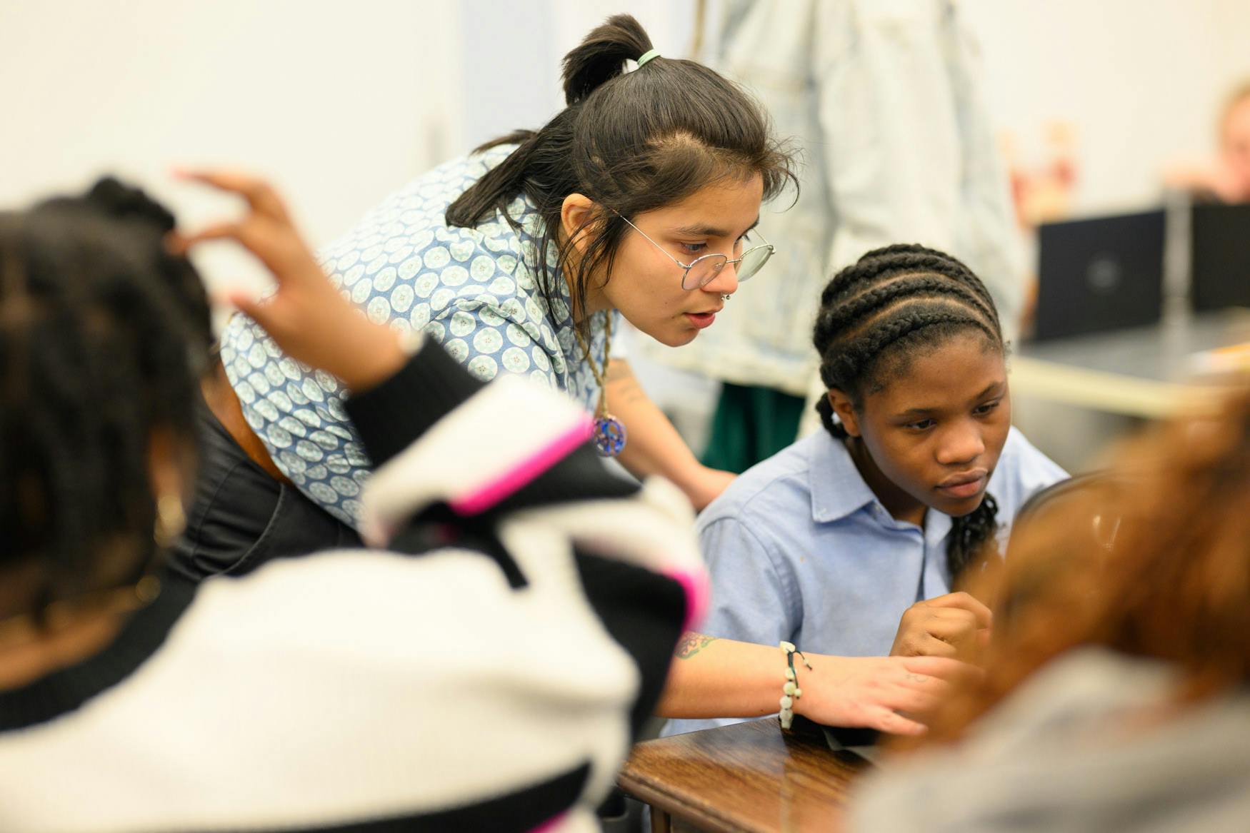 Person leaning over to help a child at a desk