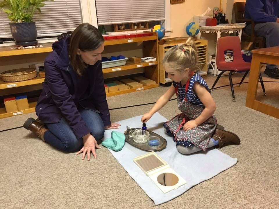 Adult and child kneeling on floor, child playing with small objects