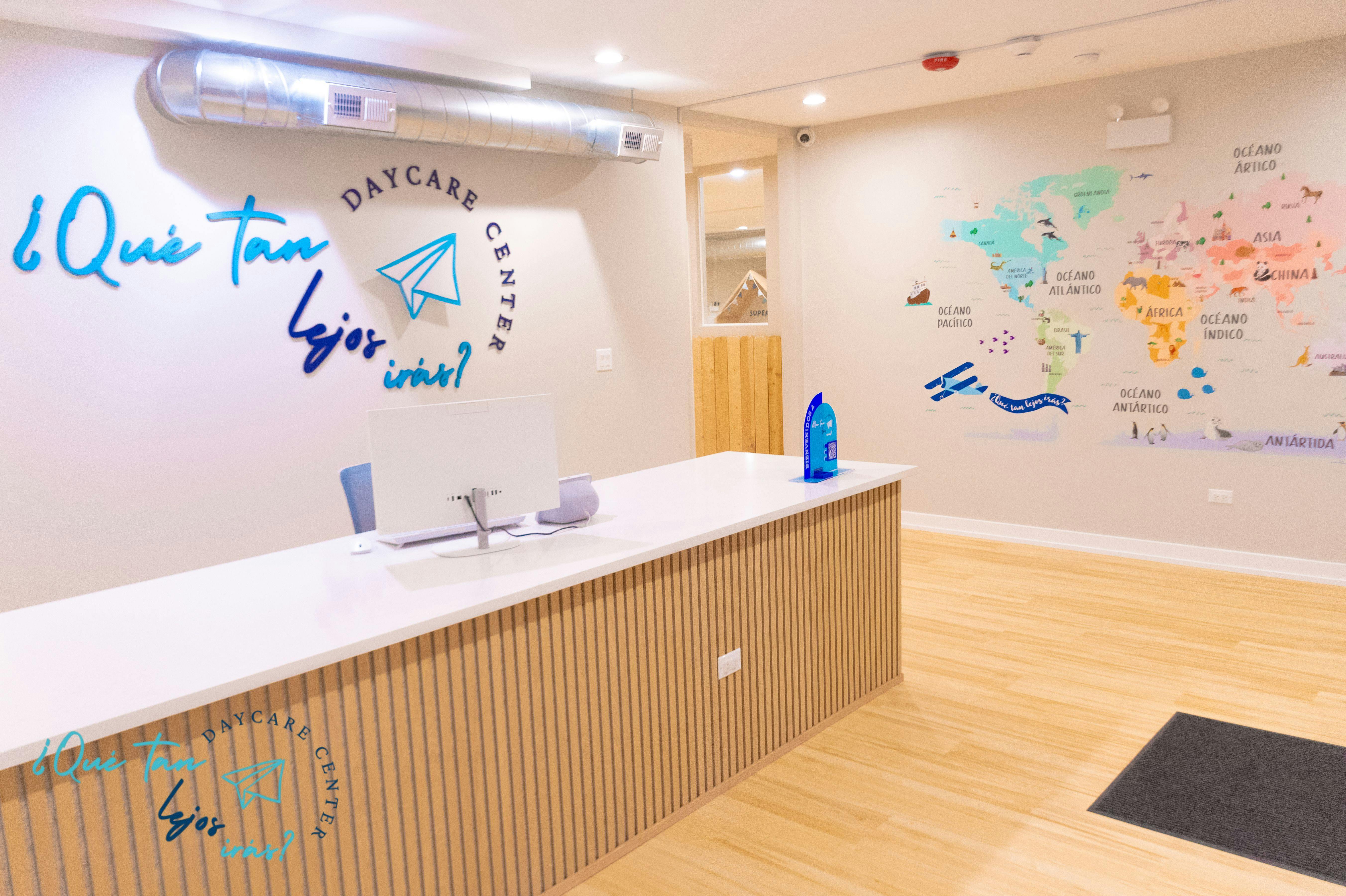 Reception area of a daycare with a white desk, computer, and a world map on the wall