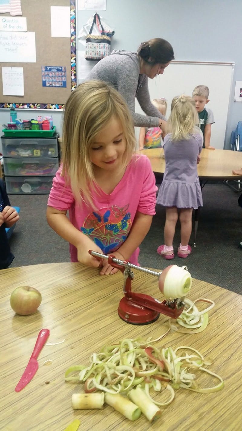 Child using an apple peeler in a classroom