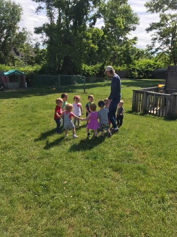 Adult and children standing in a circle on grass