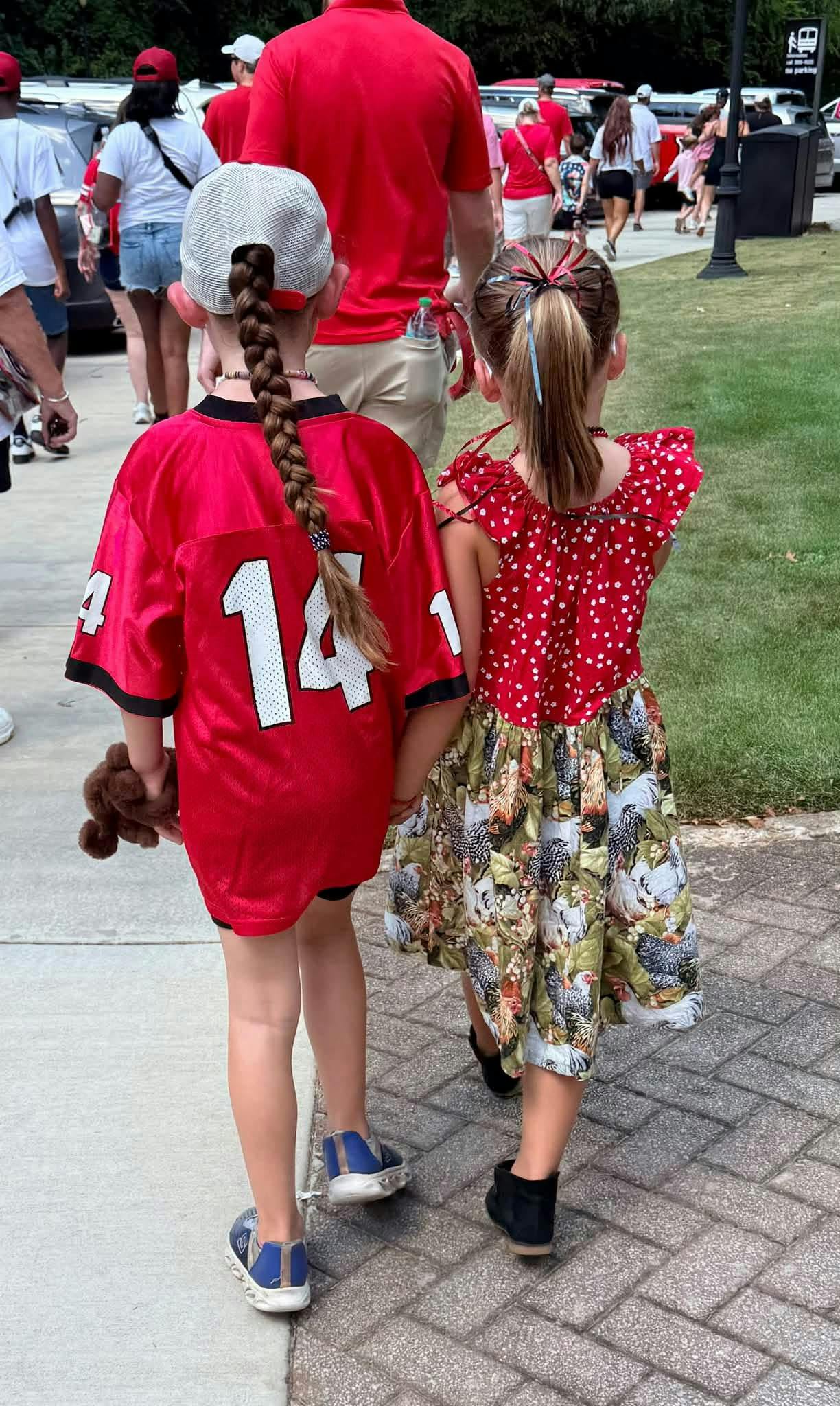 Two children holding hands walking among a crowd outdoors
