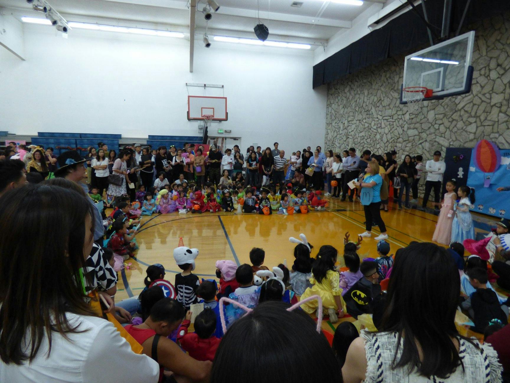 People gathered in a gymnasium, some seated on the floor