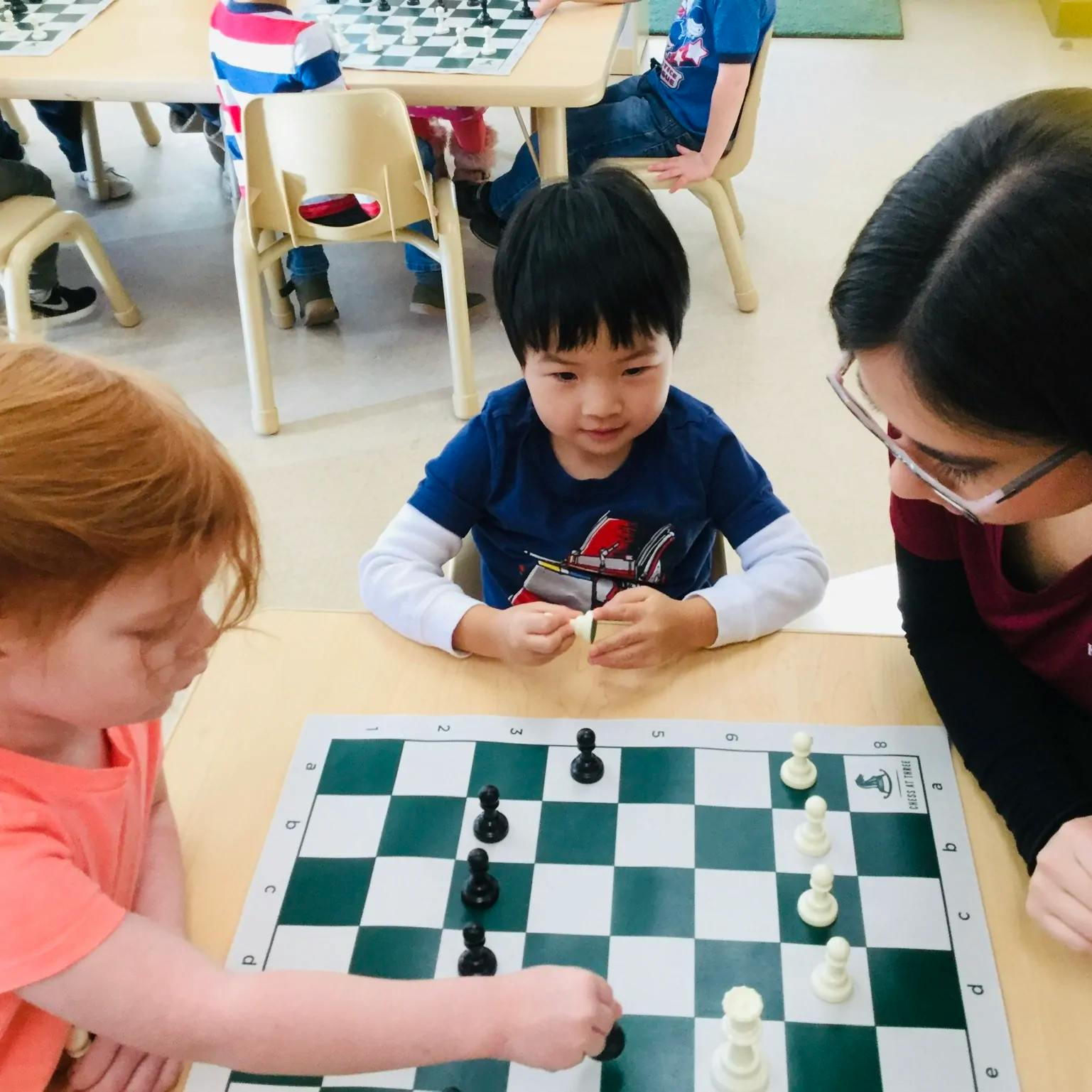 Three people playing chess at a table