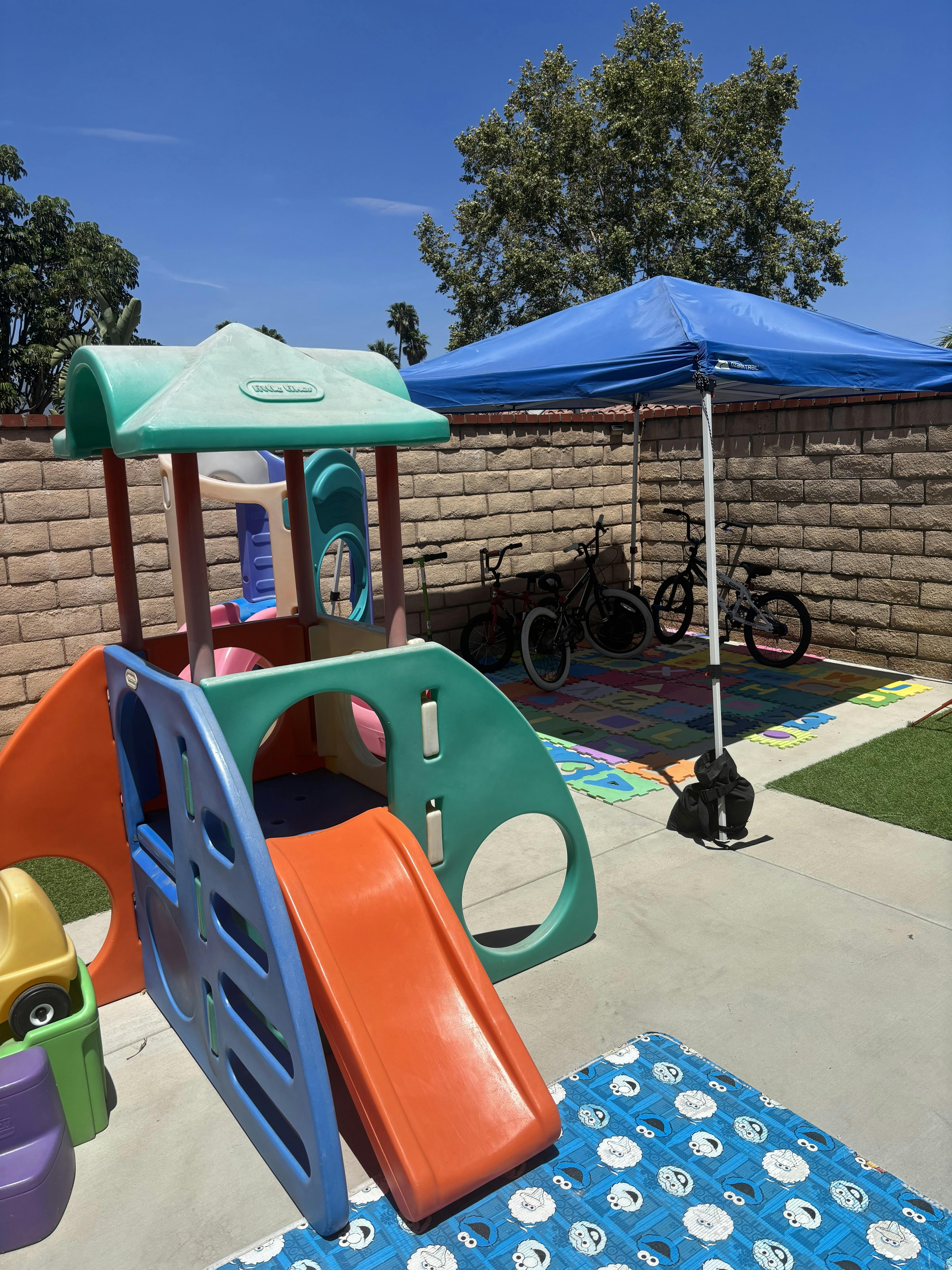 Plastic playground structure and bicycles under a pop-up canopy