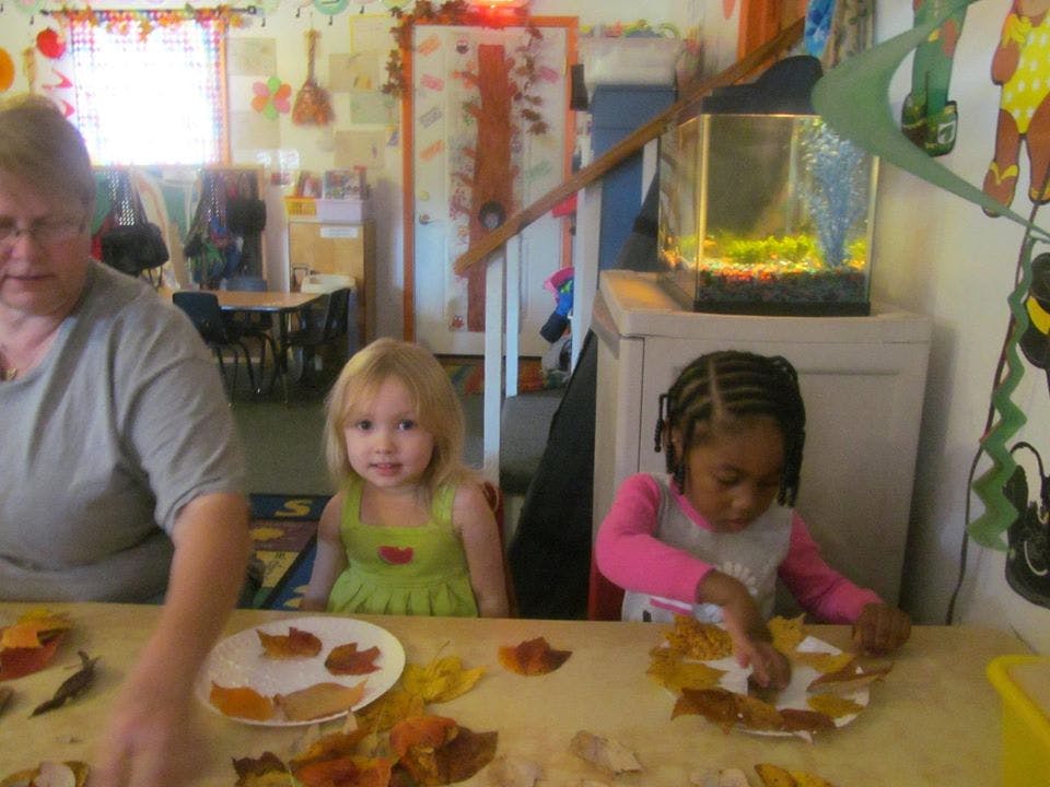 Adult and two children making crafts with leaves