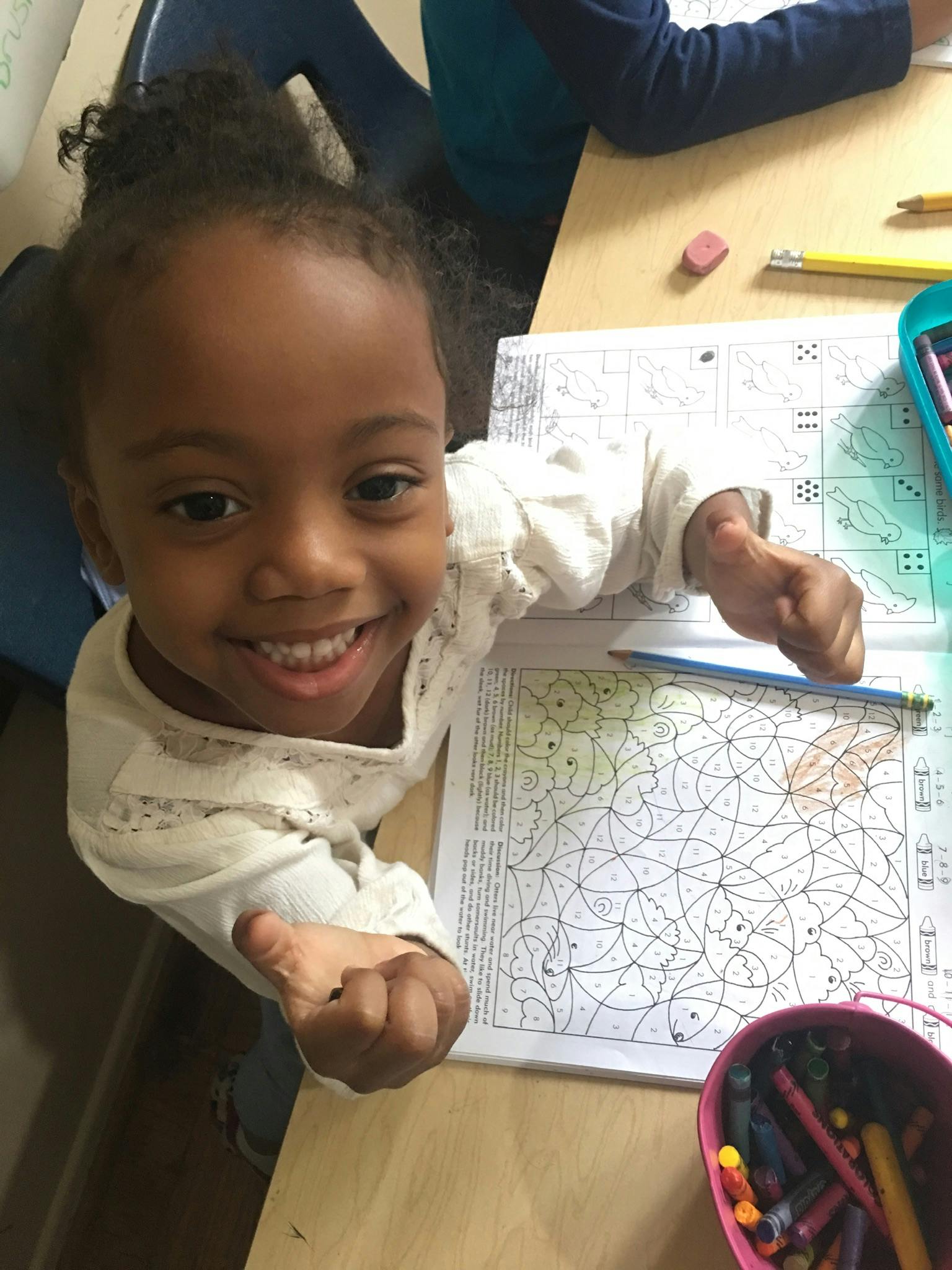Child at a desk with a coloring book and activity book