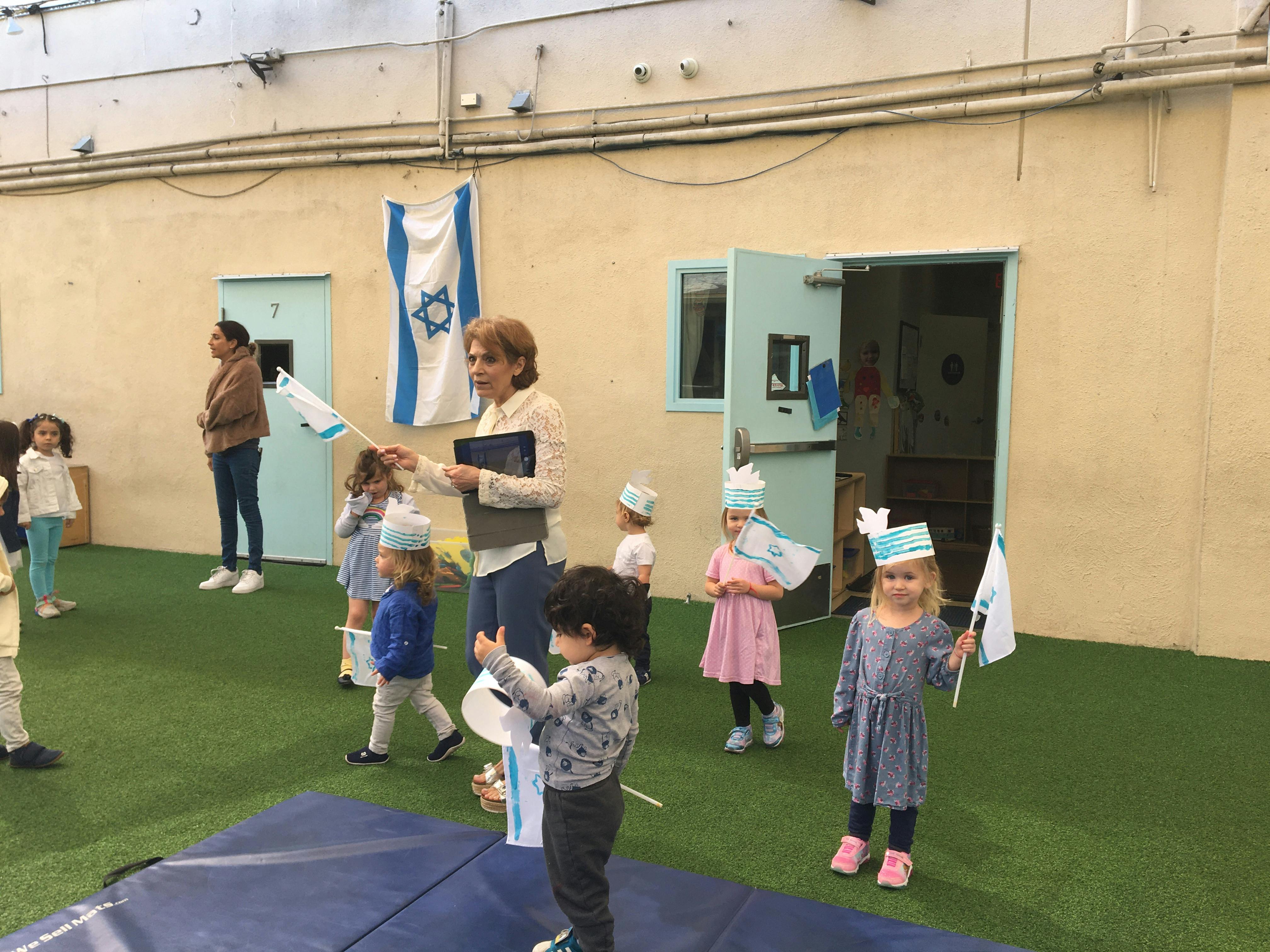 Adults and children holding flags and wearing paper crowns