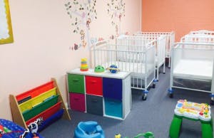 Nursery room with multiple cribs and colorful storage