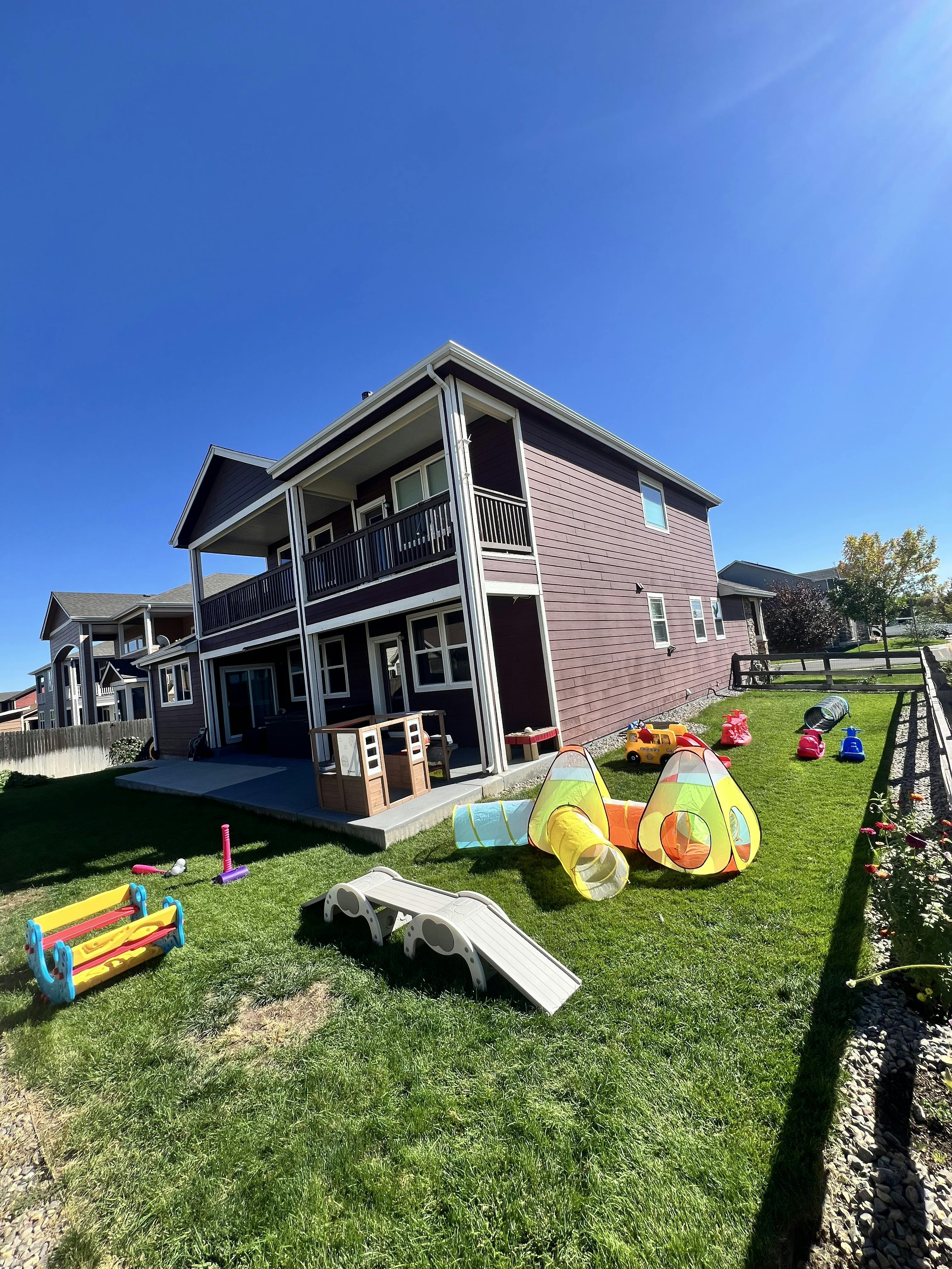 Backyard with play tunnels and outdoor toys in front of a house