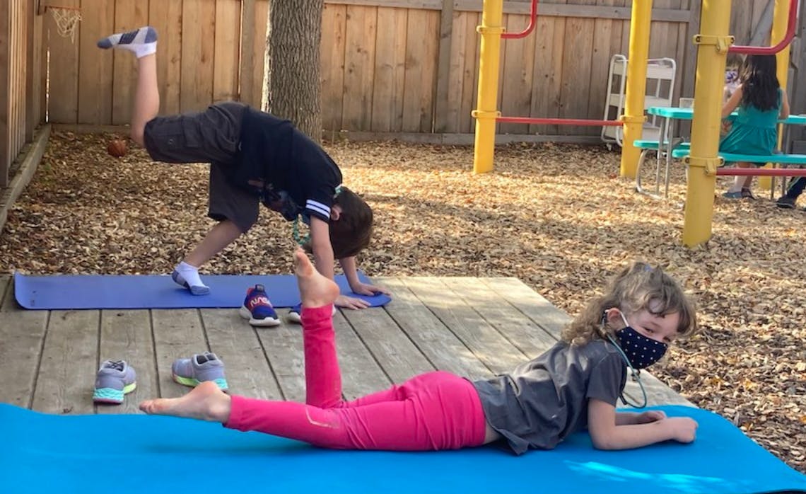 Two children exercising on yoga mats outdoors