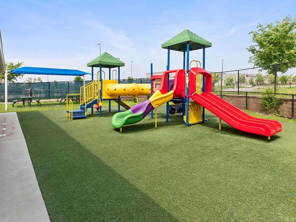 Colorful outdoor playground with slides and climbing structures on green turf