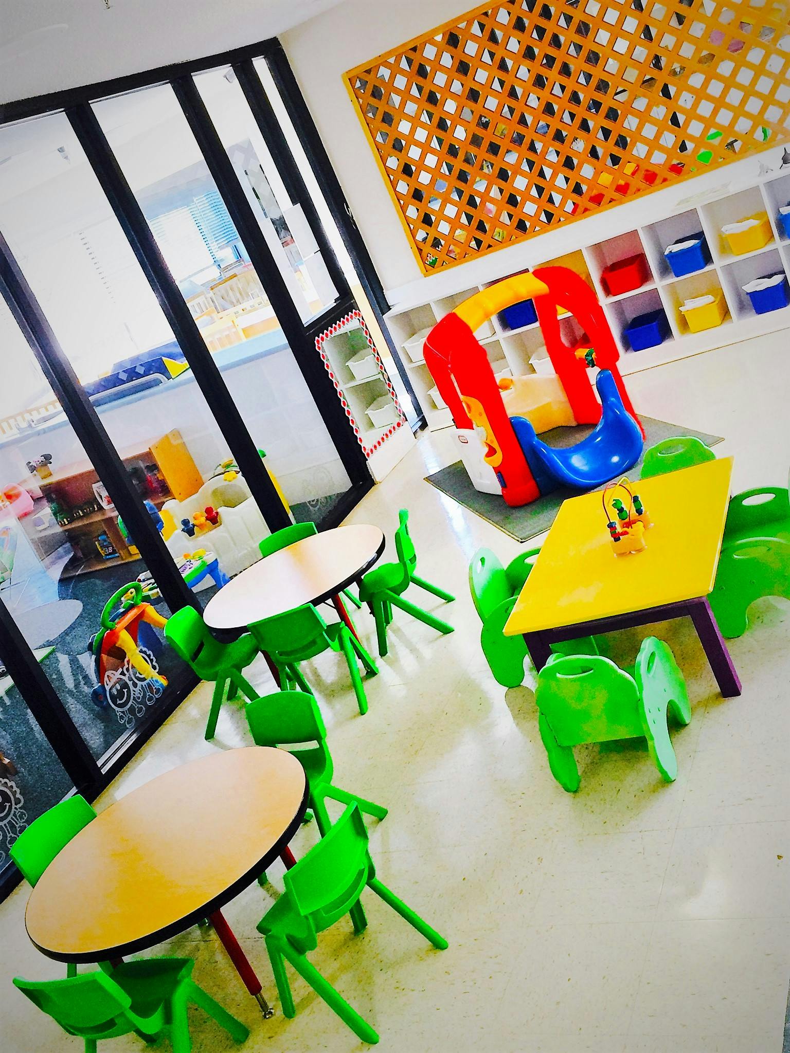 Playroom with small tables and chairs, and a colorful play structure