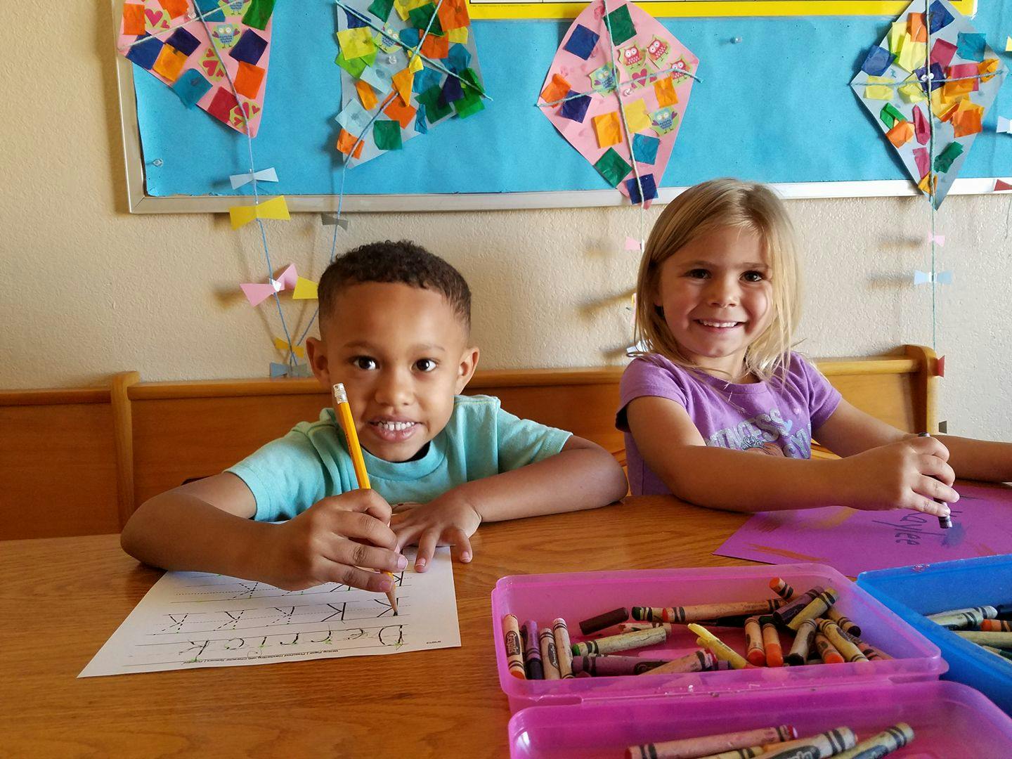 Two children drawing at a table in a classroom
