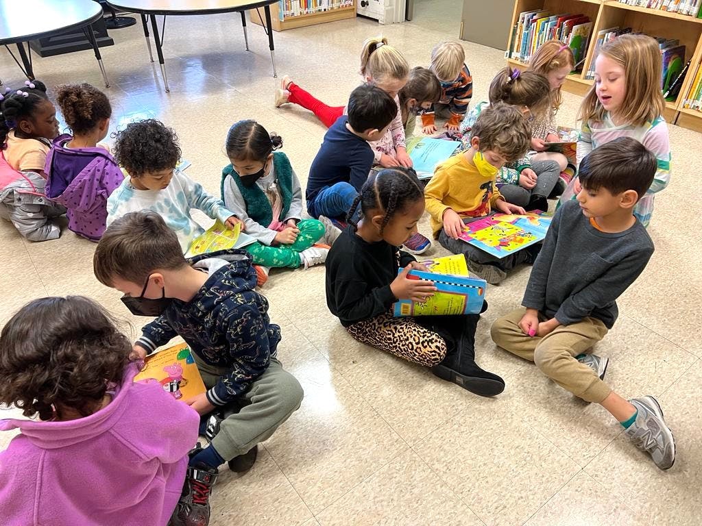 Group of children sitting on the floor looking at books