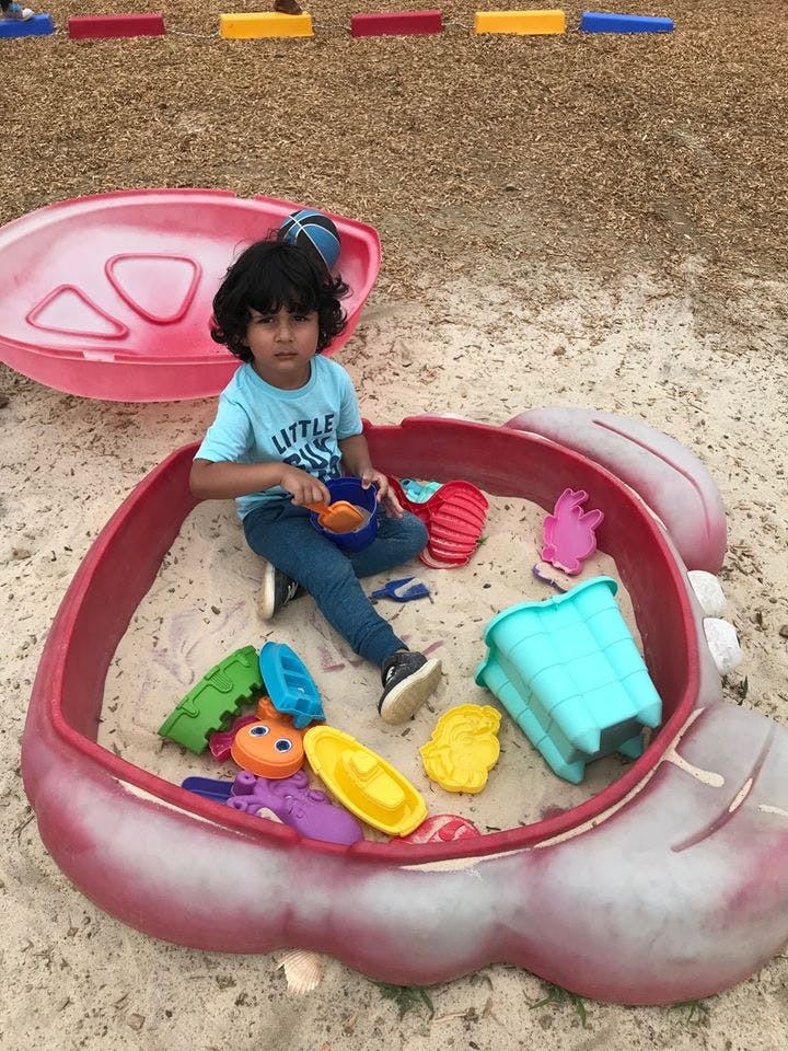 Child playing in a sandbox with toys