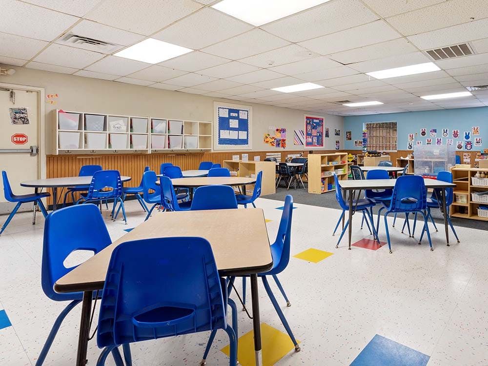 Empty classroom with small tables and blue chairs