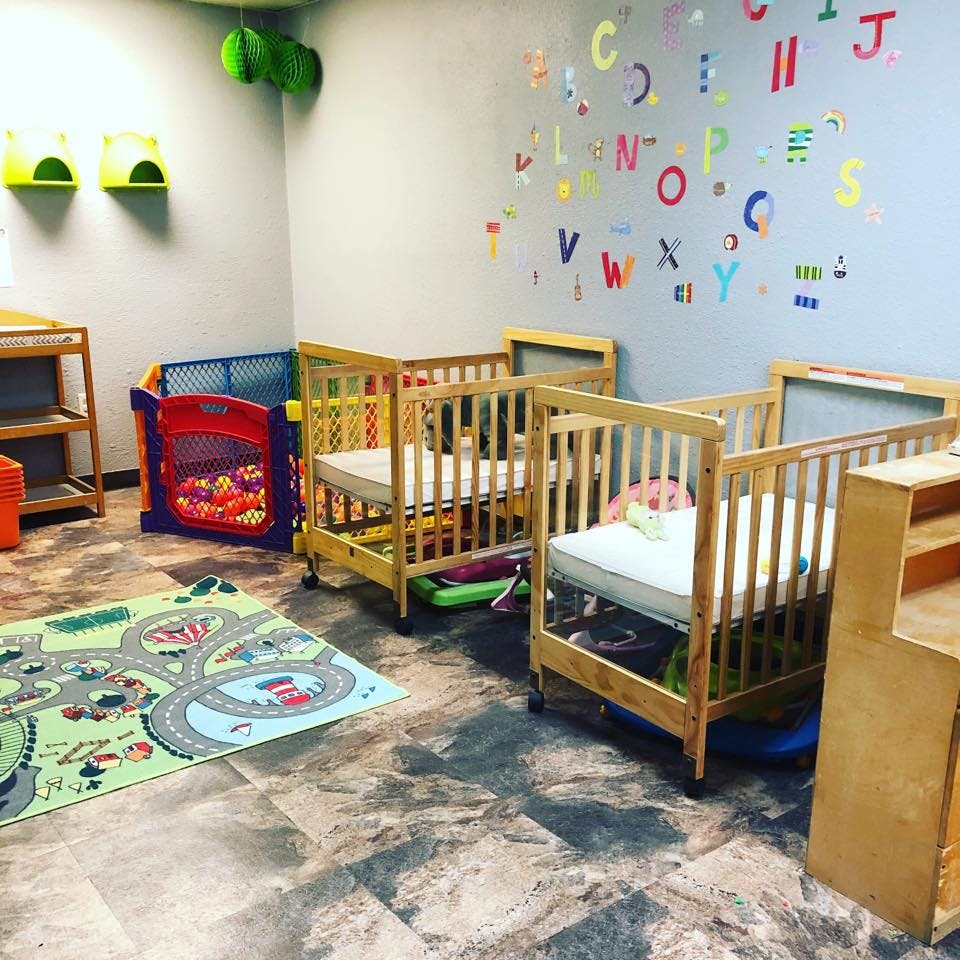 Cribs and playpen in a room with alphabet letters on the wall