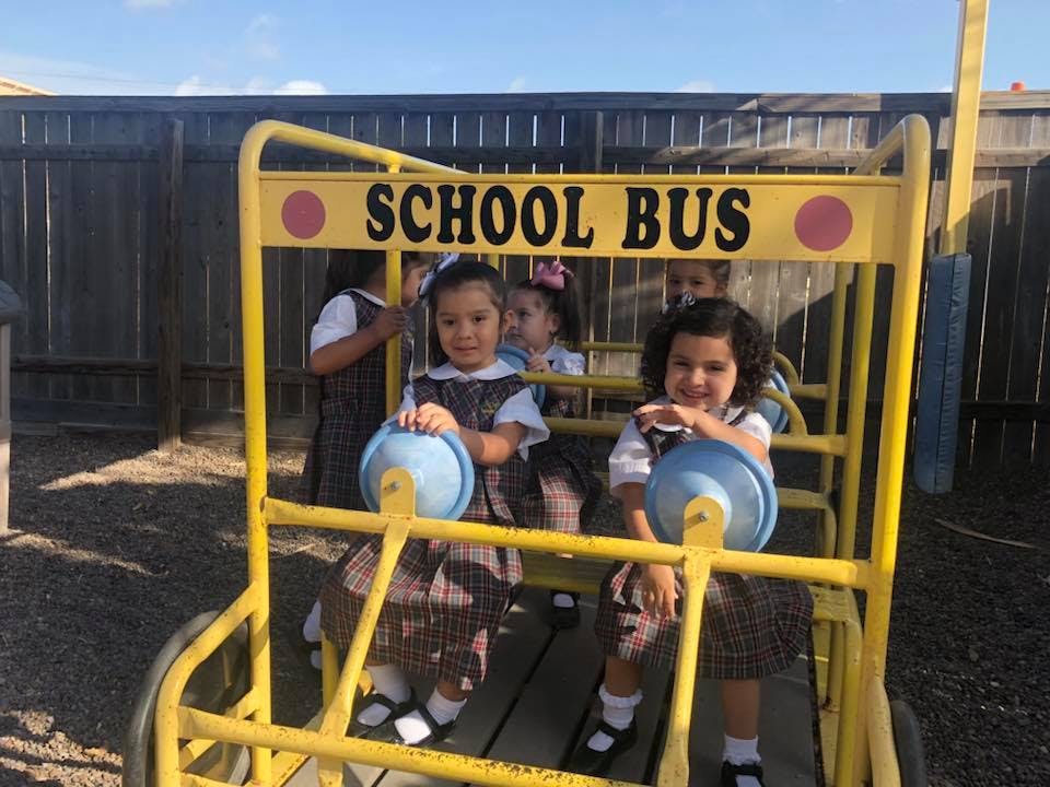 Children playing on a yellow school bus playground structure
