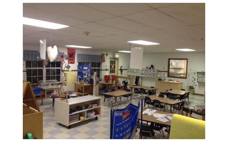 Empty classroom with tables, chairs, and learning materials