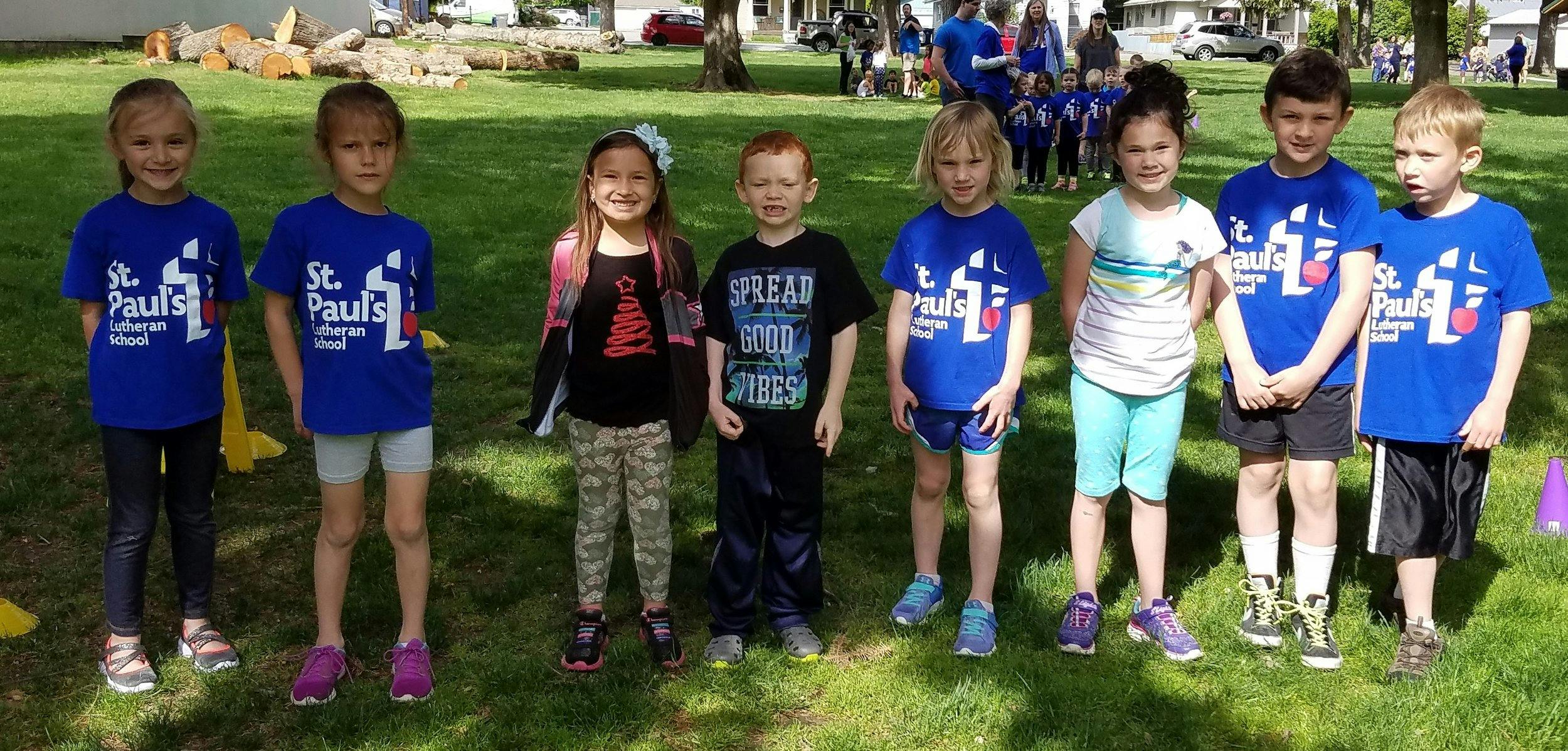 Seven children standing in a line on grass
