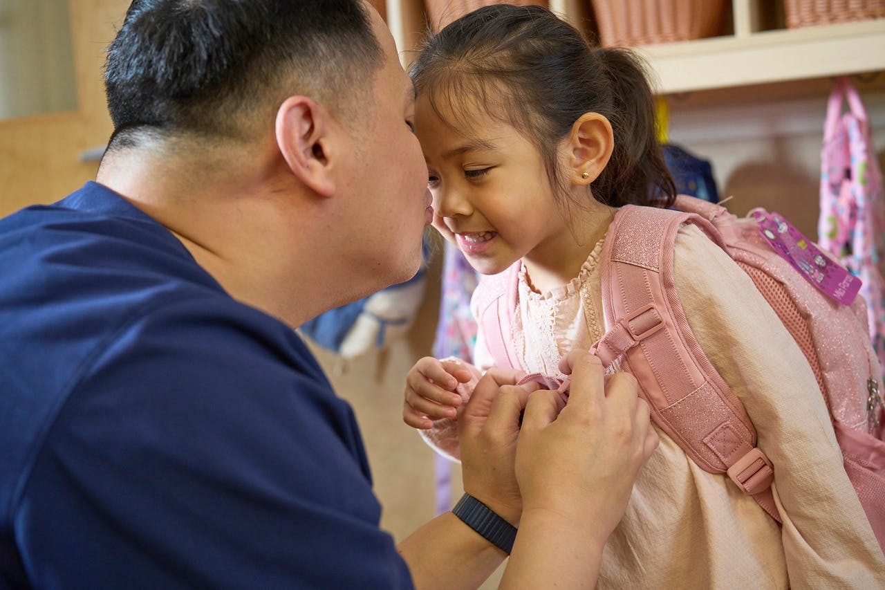 Adult and child with backpack touching foreheads