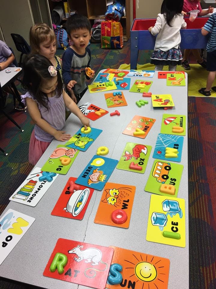 Children playing with alphabet puzzles at a table