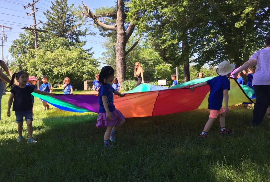 Children playing with a colorful parachute outdoors