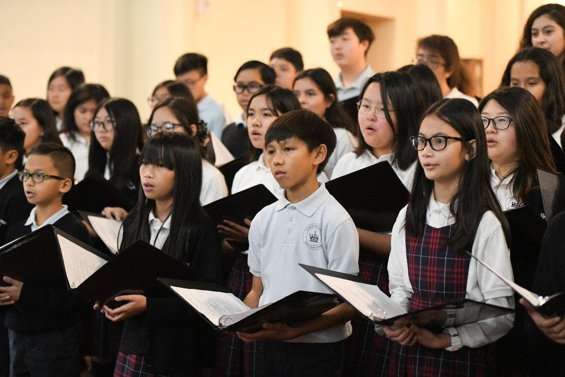 Children and teens singing in a choir, holding music sheets