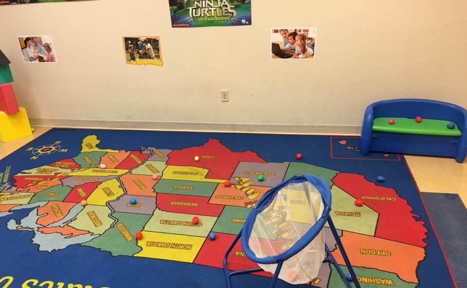 Classroom with a US map rug, small balls, and a toy basketball hoop