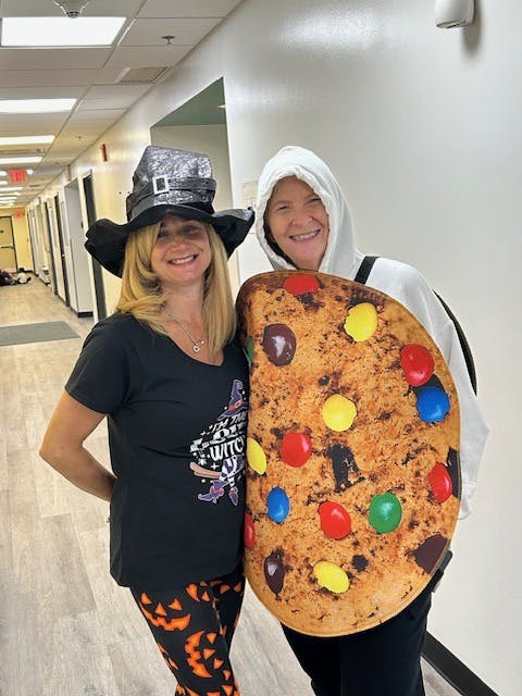 Two people in costumes, one dressed as a witch and the other as a cookie