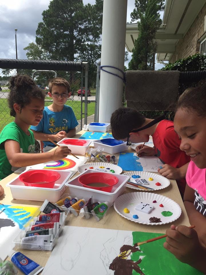 Children painting at a table outdoors