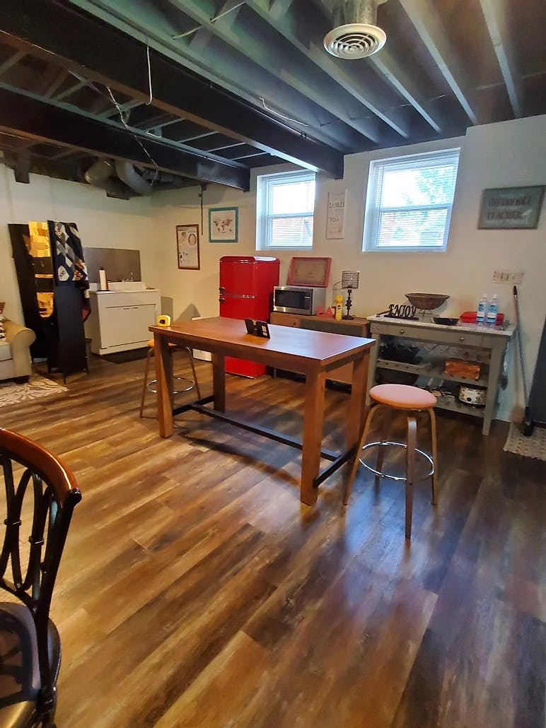 Basement room with wood floor, red refrigerator, and wooden table