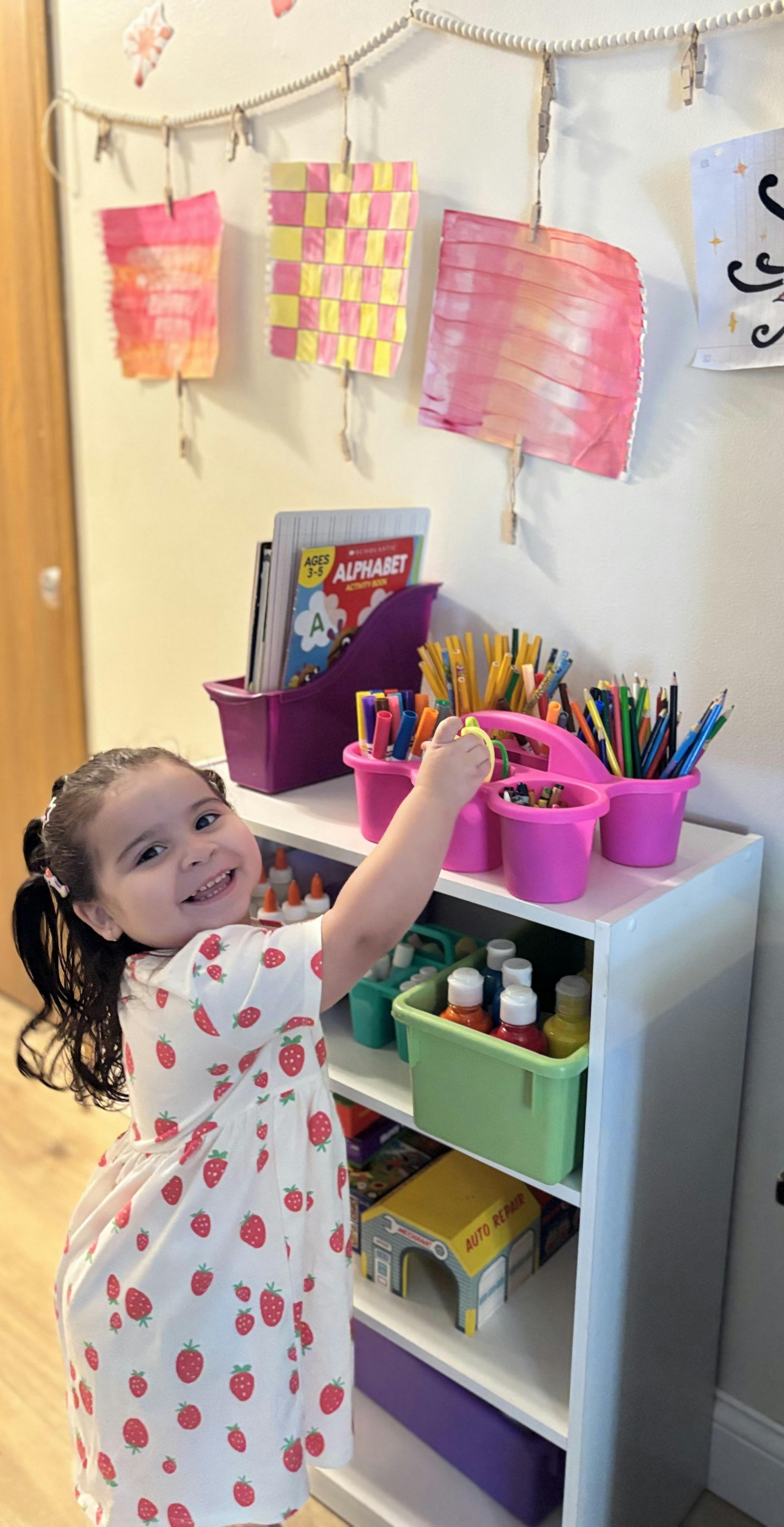 Child reaching for art supplies on a shelf