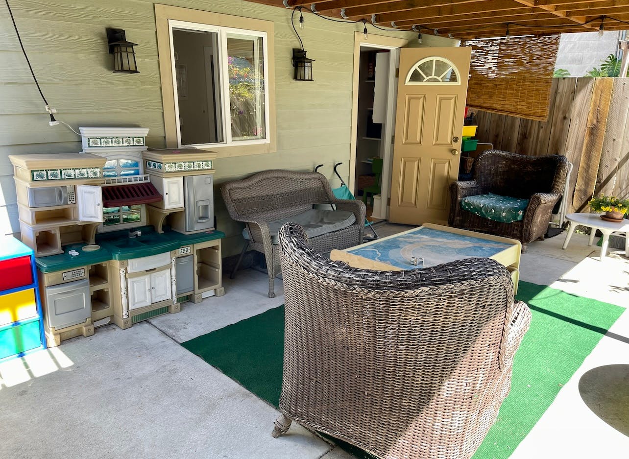 Outdoor patio with a play kitchen, wicker furniture, and a door