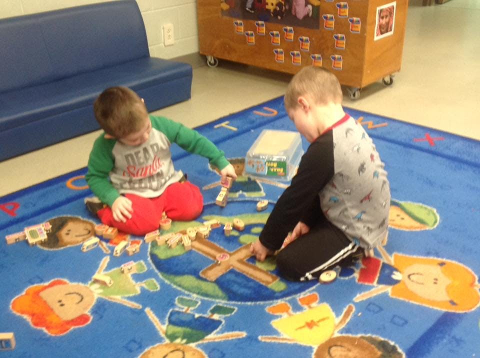Two children playing with wooden blocks on a rug