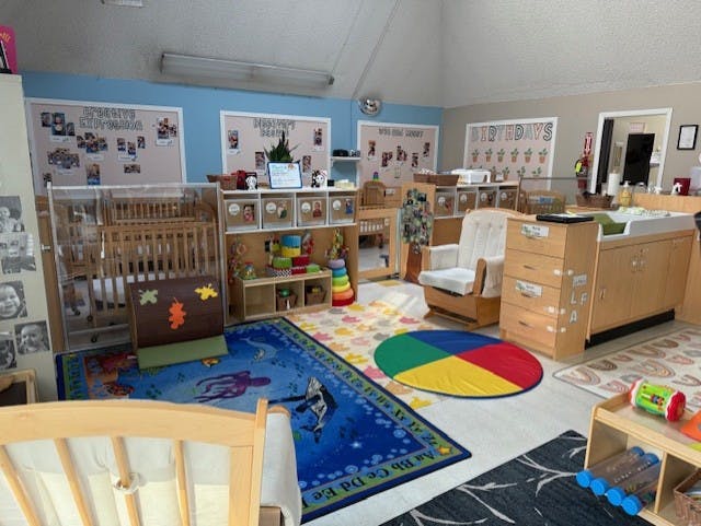 daycare classroom with multiple cribs, changing station, and play areas