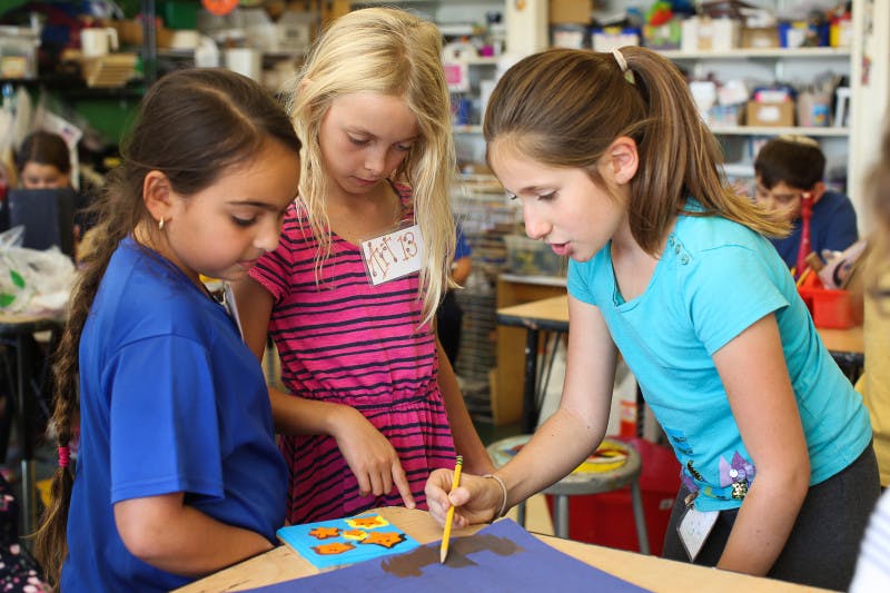 Three children working on an art project in a classroom