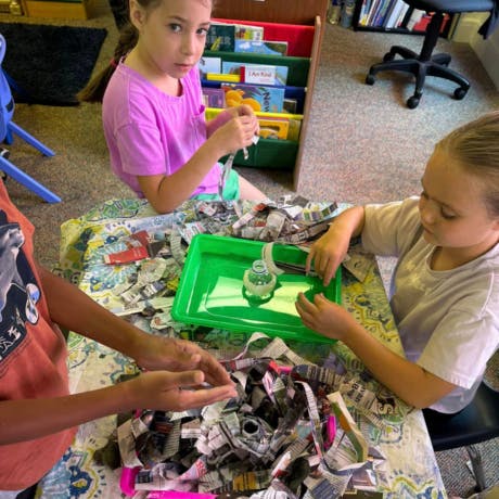 Three children making crafts with shredded paper
