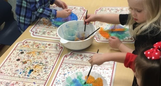Children painting with brushes and colorful dyes