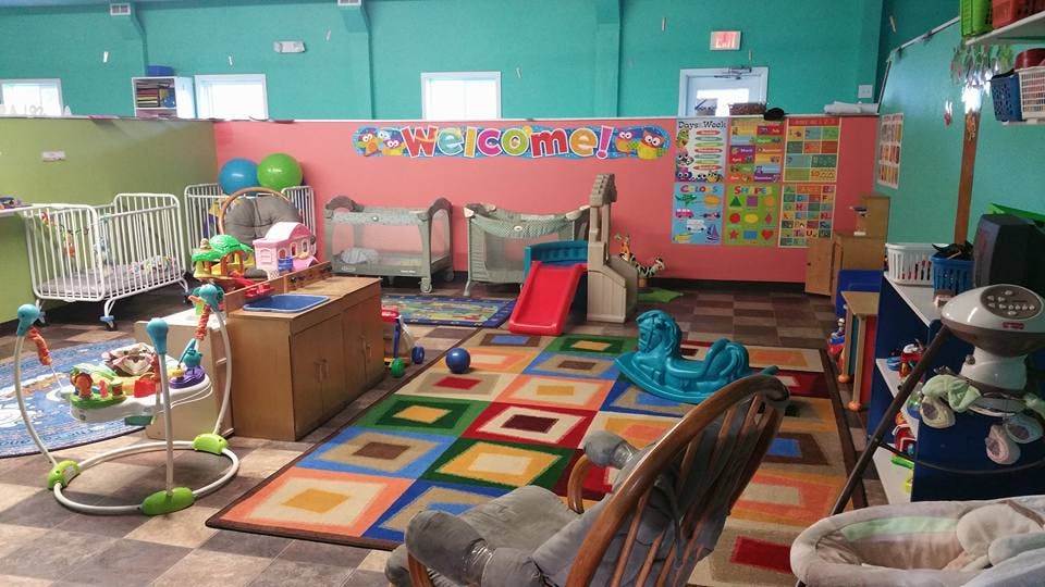 Playroom with cribs, colorful rug, and toys