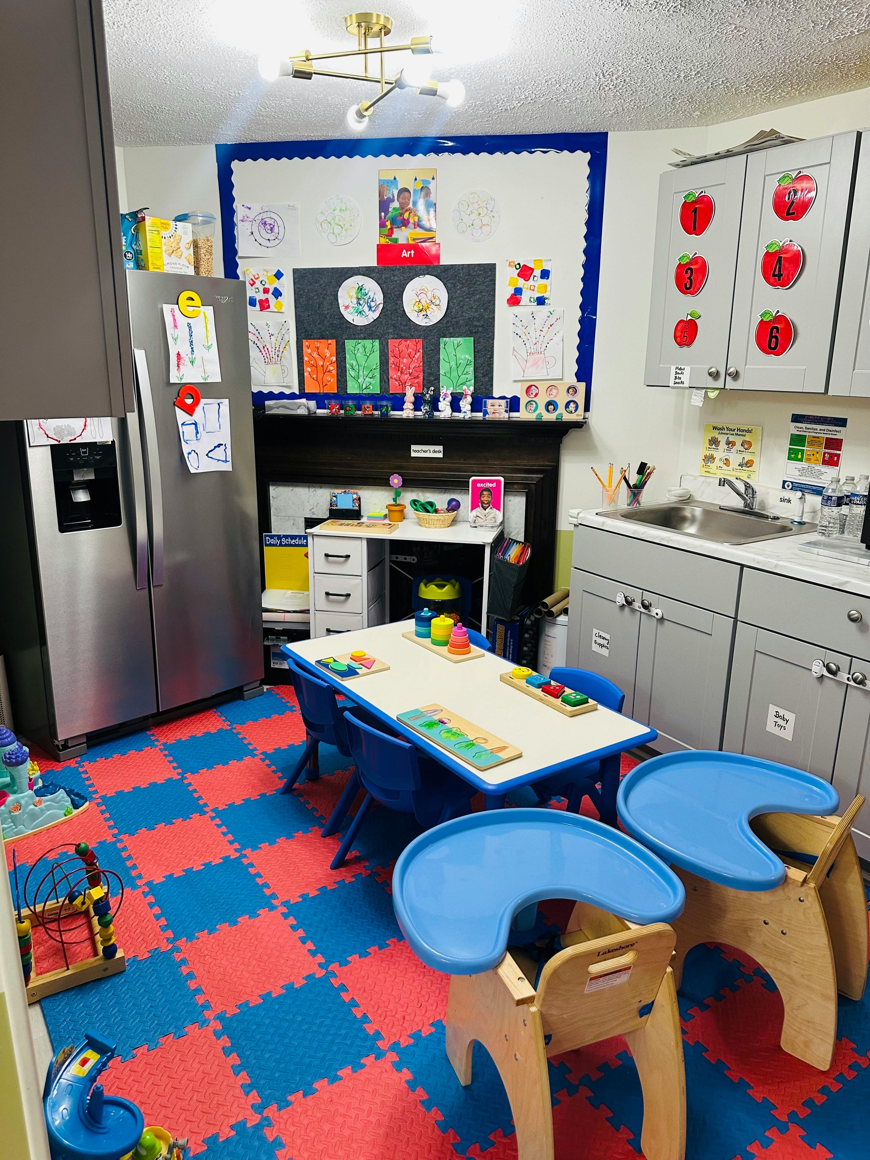 Classroom with child-sized table and chairs, kitchen area, and art display