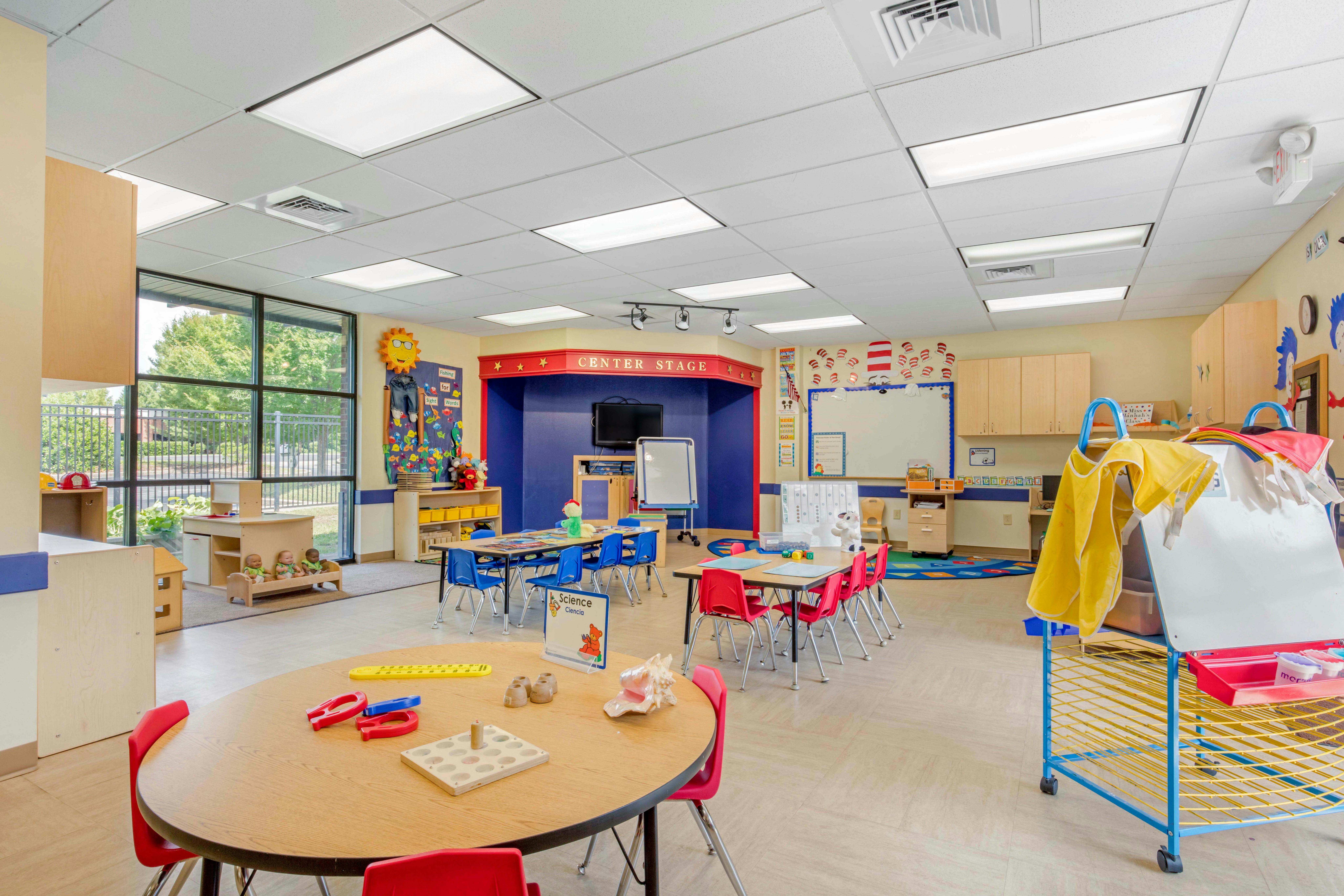 An empty early childhood classroom with small tables and chairs