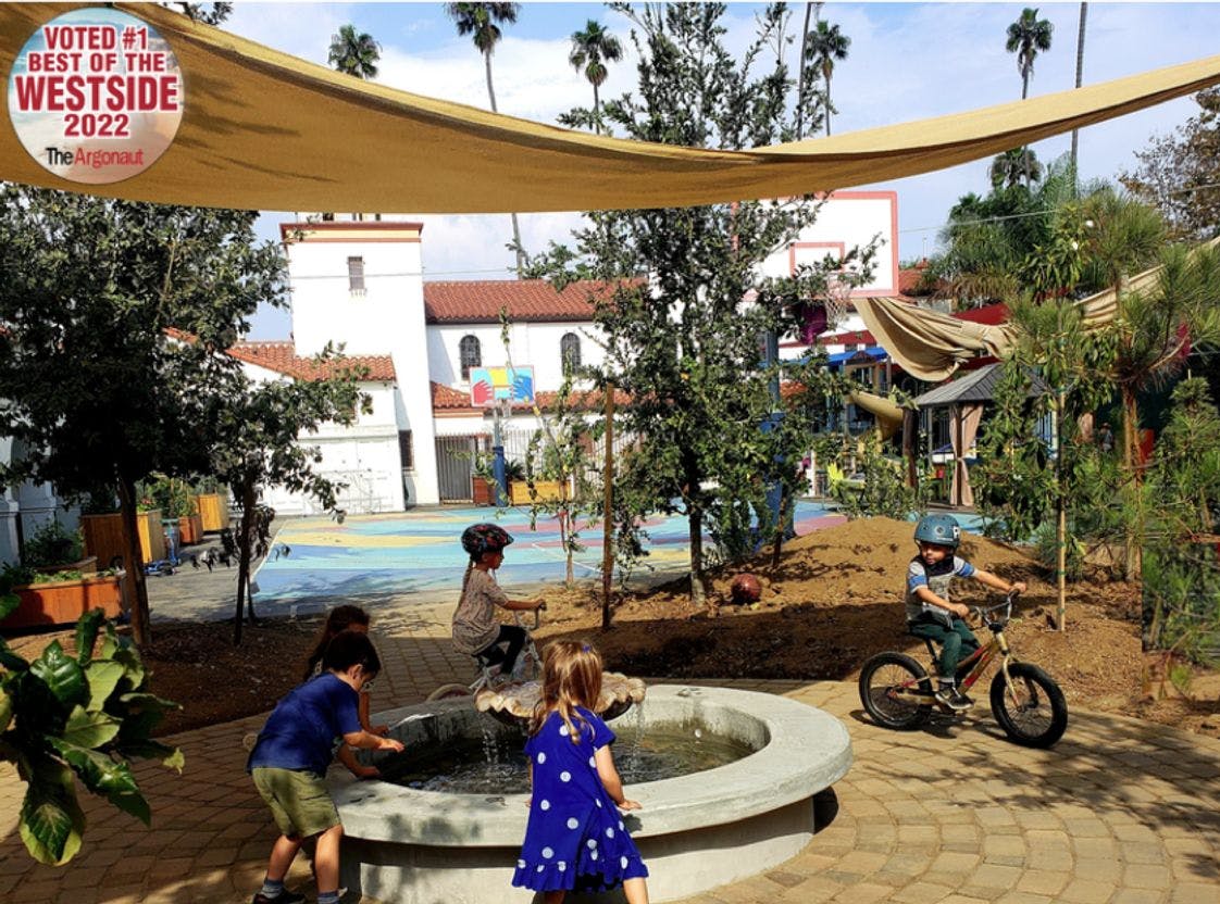 Children playing in a courtyard with a fountain and a child on a bike