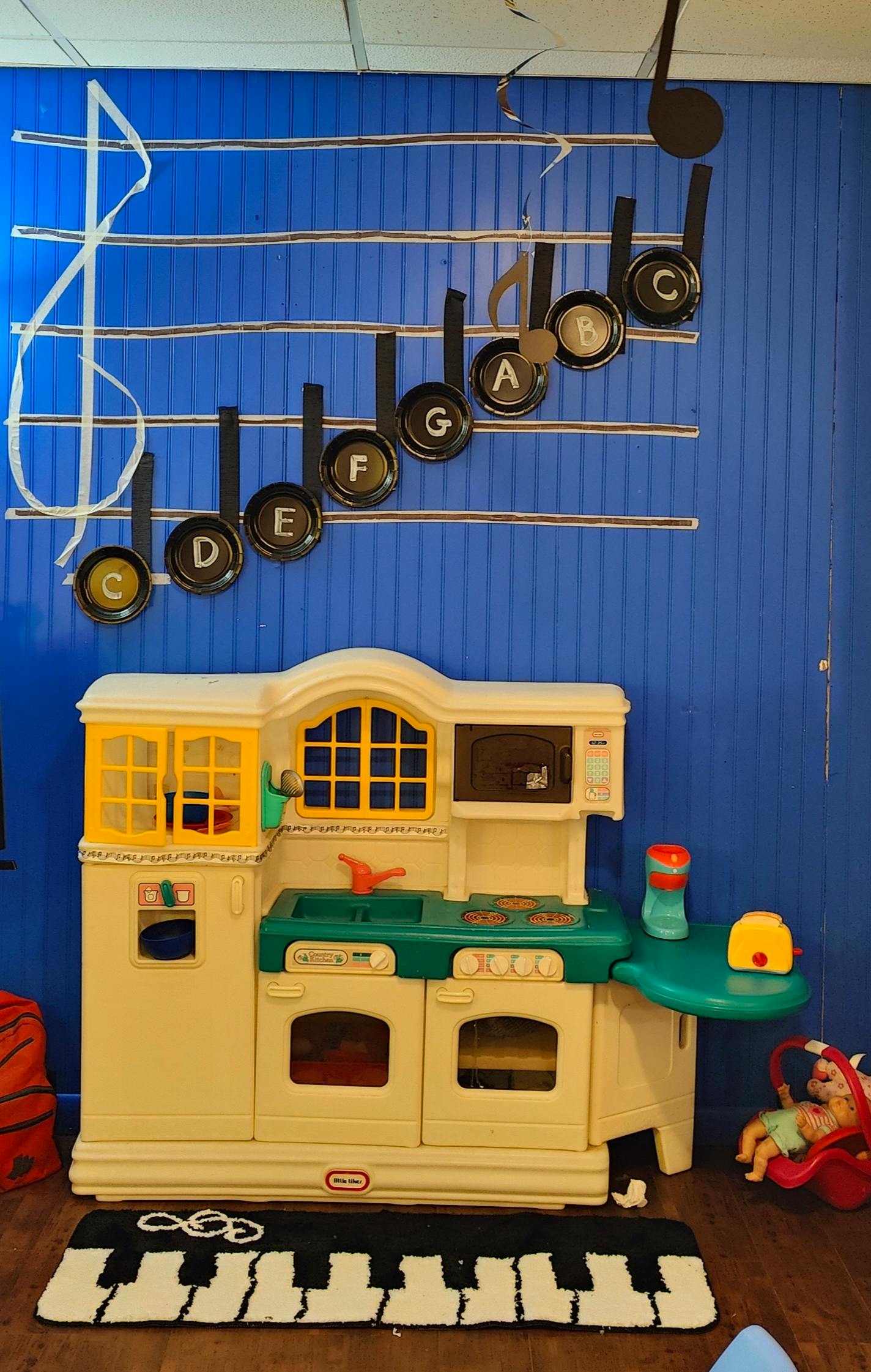 Play kitchen with a piano mat and musical notes on a blue wall